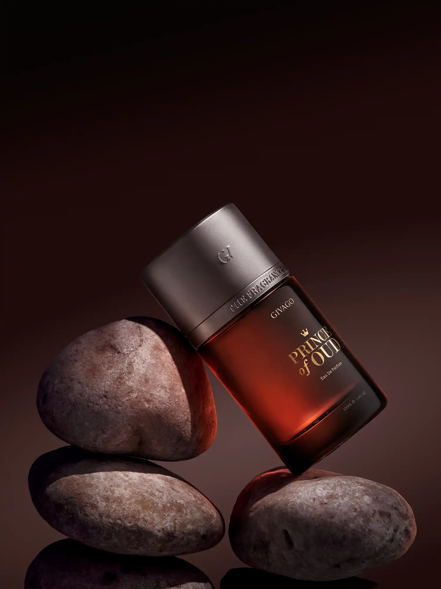 svg+xml;charset=utf - commercial photography studio Egypt Givago Prince of Oud perfume photography: amber bottle balanced on stacked river stones against a dark brown backdrop