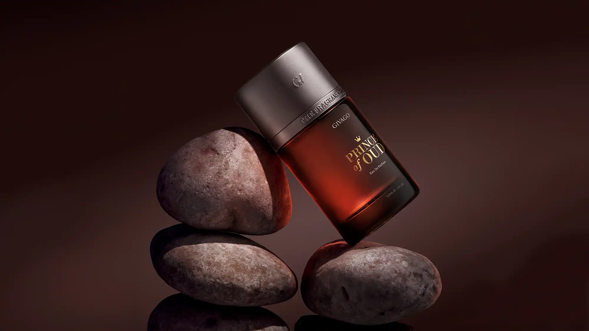 Givago Prince of Oud amber perfume bottle balanced on stacked river stones against a dark brown backdrop
