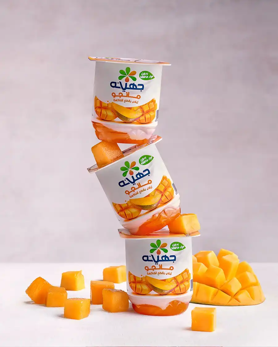 Juhayna mango yogurt packs stacked with fresh fruit - Egyptian food photography